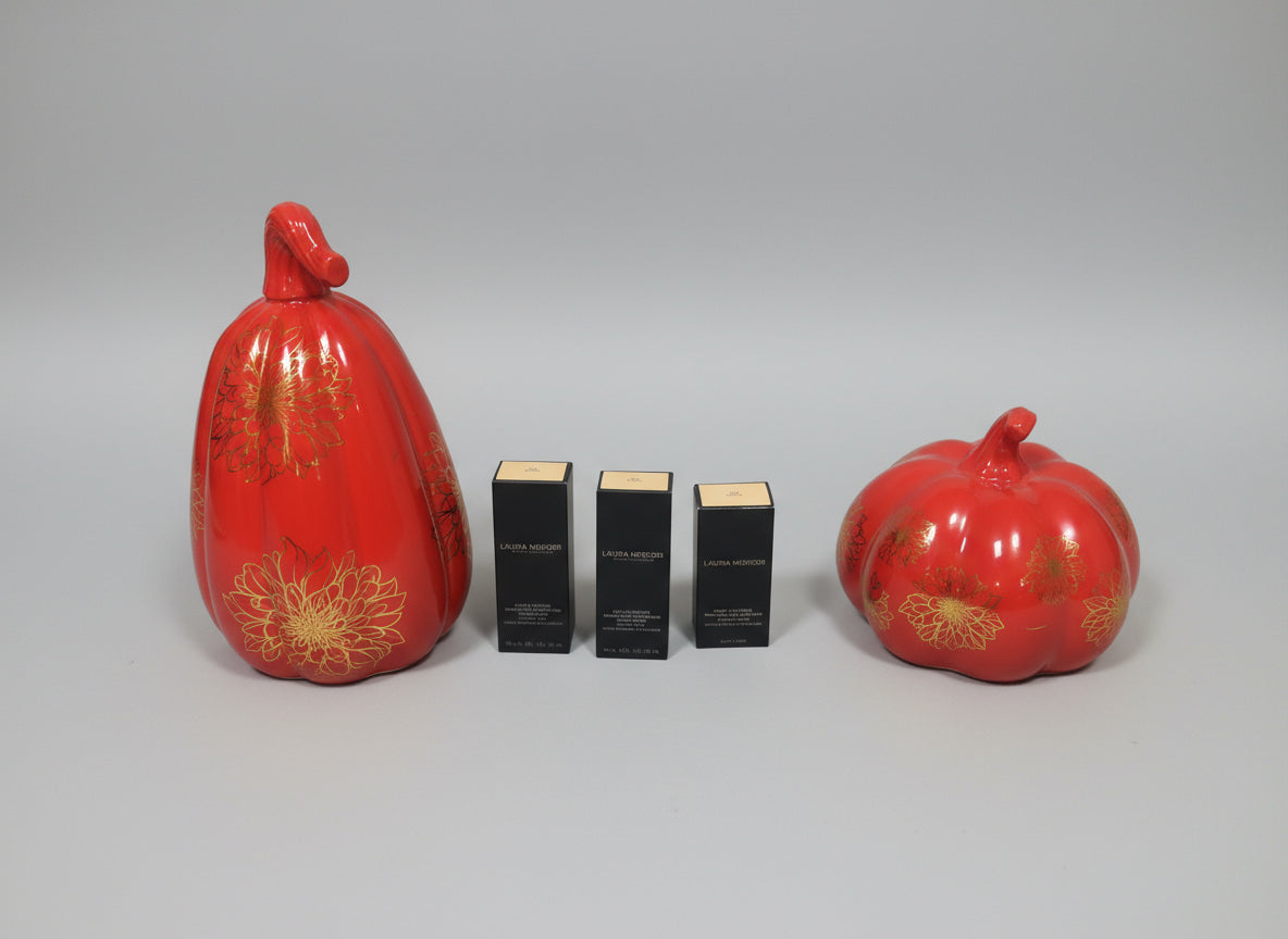 Two red decorative pumpkins and three black boxes with gold accents 