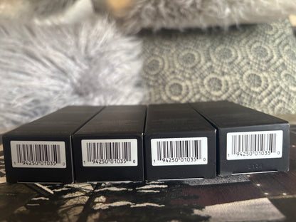 Four black boxes with barcodes on a textured surface Laura Mercier 